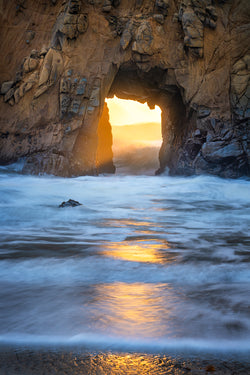 Landscape photography, Sunset glow through an arch in big sur california. 