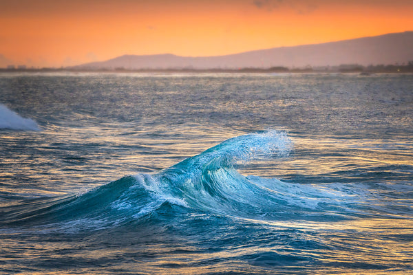 A breaking wave at sunset on oahu hawaii. 