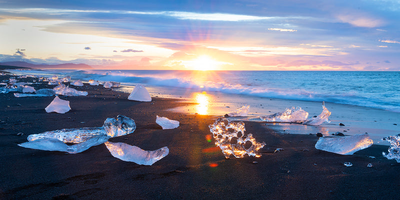 sunrise light backlights glaciers on diamond beach in iceland.