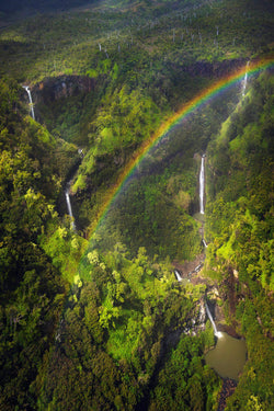 Hawaiian Landscape photography by Lijah Hanley. A rainbow appears above waterfalls in Kauai Hawaii along the Napali coast.