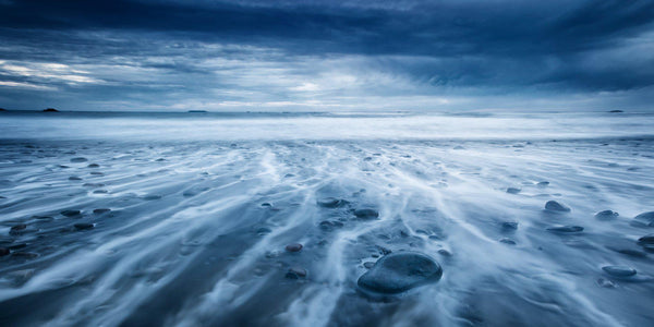 Photograph of waves receding through rocks on a stormy day on the Washington Coast. 